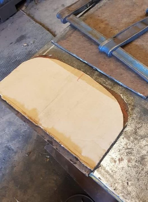 Kartongmall placeras på metallplåt i verkstad för att markera böjning och kapning.