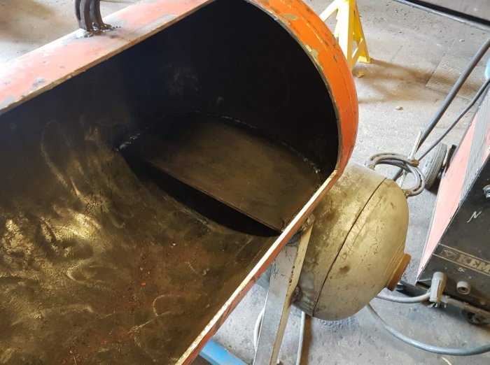 Avkapad metallplåt med böjning intill svetsutrustning och verktyg i en verkstad.