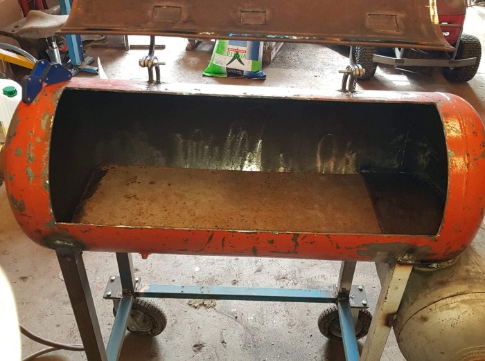 En stor plåt som är lätt böjd i en orange hydraulisk press för att leda fett mot mitten.