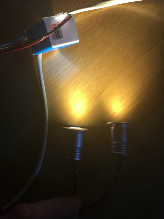 Två LED-lampor anslutna till en drivkrets, en tänd och en släckt, på en träyta.