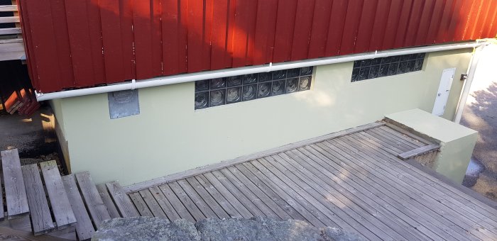 Betonggarage med träterrass och röd plåttak, avsett för viktbedömning för spabadinstallation.