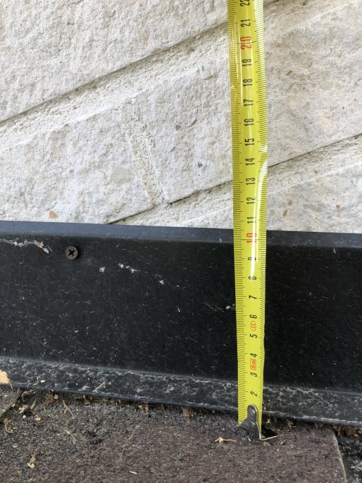 Måttband som visar höjden på ståndplåt vid en fasad, står på 12 cm.