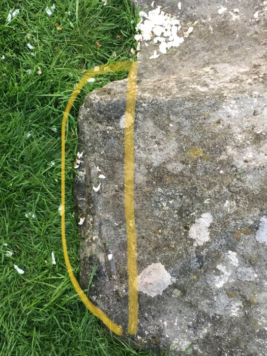 Stor sten på gräsmatta med en inringad sektion markerad med gult för potentiellt borrningsarbete.