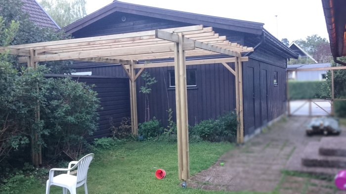 Pergola med knippepelare och bärande balkar placerade med 45mm distans i en trädgård.