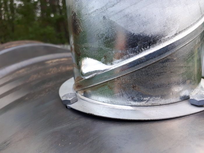 Aluminium ventilation tube connected to metal base as part of a homemade pizza oven project.