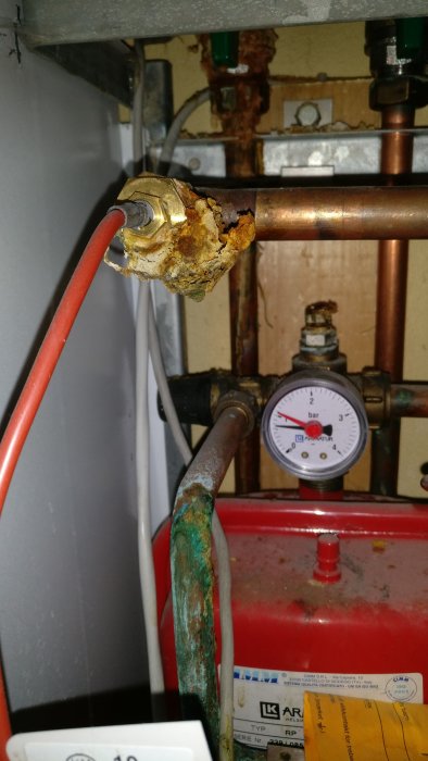 Rost och korrosion på fjärrvärmeaggregatets koppling och rör, med fokus på en koppling med kraftig rostbildning.