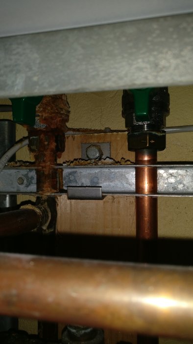 Fjärrvärmeaggregat med synlig korrosion och avlagringar på rör och vägg.