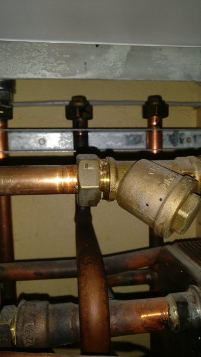 Kopparledningar och komponenter med tecken på korrosion vid en anslutning i ett fjärrvärmeaggregat.