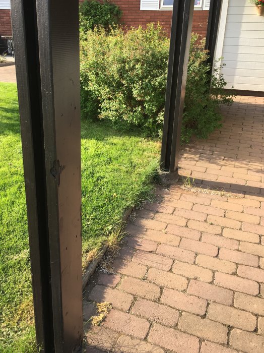 Skadade trästolpar på en carport med synlig murknad vid kontaktpunkten med betongplinten.