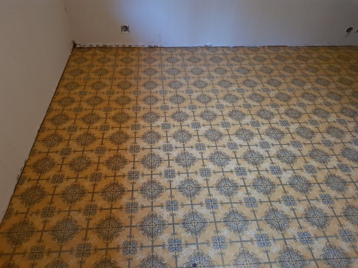 Gammal gul och blå 70-tals plastmatta med mönster, delvis uppriven under renovering.