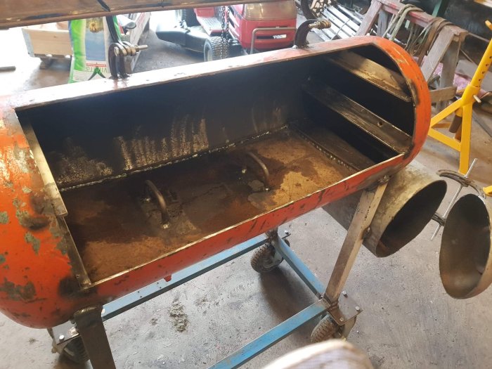 Svetsad metallbehållare med handtag på verkstad, värmedeformation synlig.