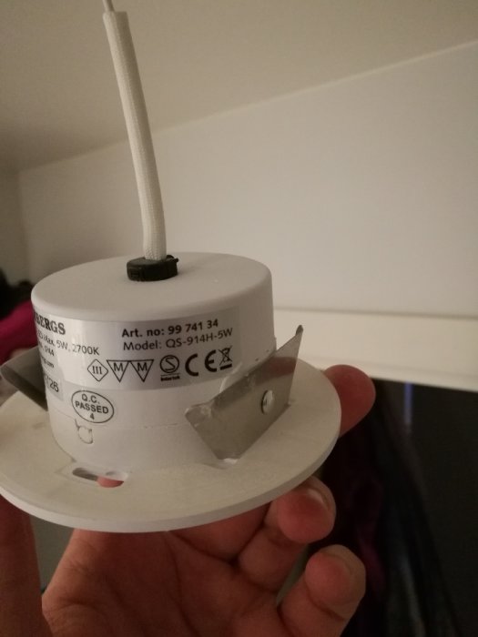 Hand håller en LED-spotlight modul som inte har synliga skruvar eller öppningsmekanismer.