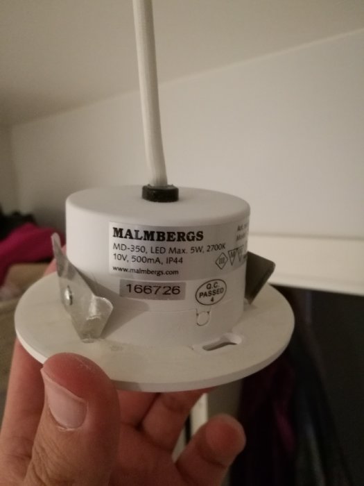 Hand håller i en LED-spot från Malmbergs utan synliga skruvar eller öppningsmekanismer.