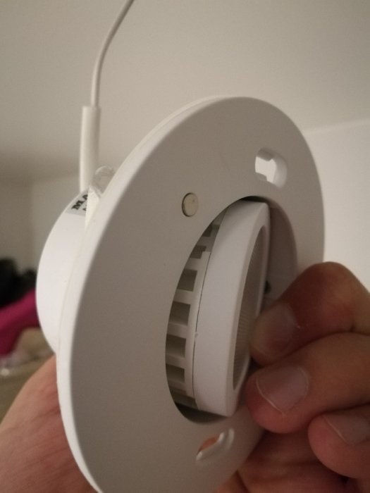 Närbild av en hand som håller en infälld spotlight där inga skruvar är synliga.