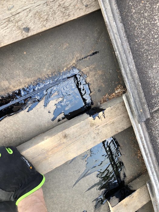 Takrenovering med ny skiva och asfaltskitt applicerat för att täppa till ett hål i taket.