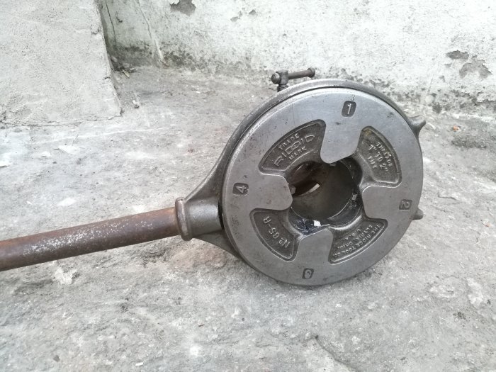Begagnad svart gjutjärnsvinsch på betonggolv, köpt för tryckluftsprojekt i garage.