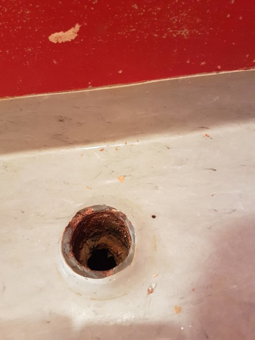 Gammalt gjutjärnsavlopp som sticker upp från ett badrumsgolv, behöver anpassning för ny toalett.