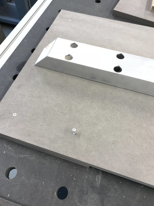 Aluminiumprofil med hål, ligger på ett arbetsbord redo att spännas fast i skruvstycke.