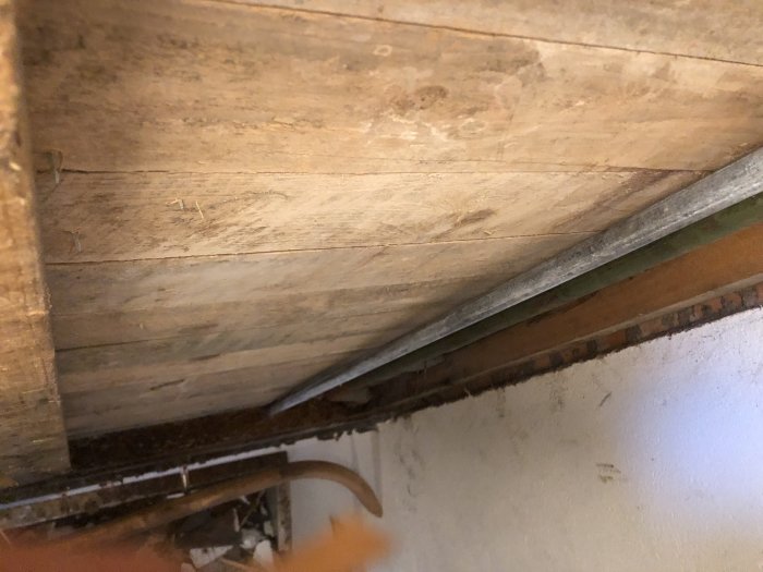 Trävägg och reglar med möjlig mögelpåväxt och vattenskador, tagen inifrån ett trapphus.