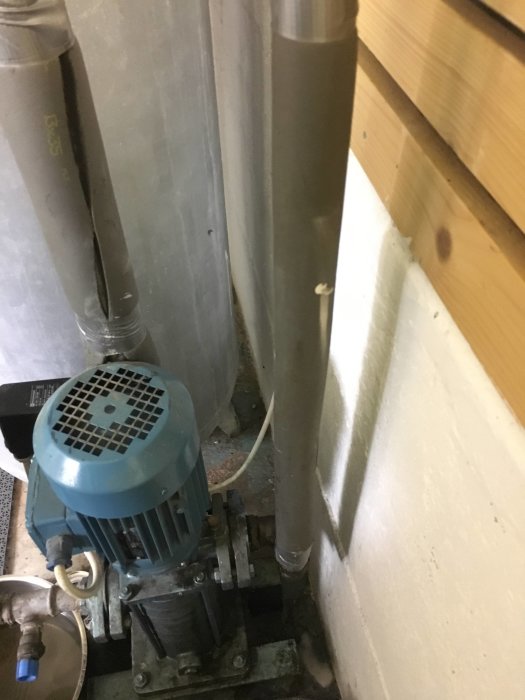 En ejektorpump och rörsystem i ett källarutrymme, med synliga rörledningar och en del av en hydrofor.