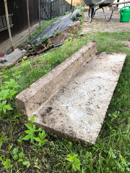 L-formade betongtrappsteg nedmonterade för renovering, med trädgårdsredskap och skottkärra i bakgrunden.