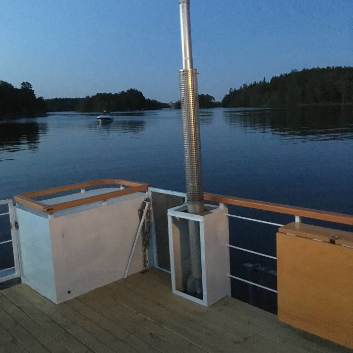 Utsikt från en båt vid ankar i skymningen med lugnt vatten och en annan båt i bakgrunden