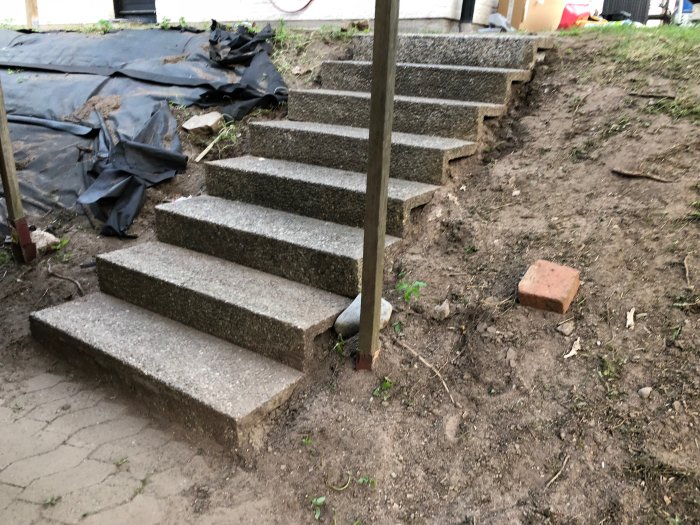 Nybyggd trappa i betong utomhus med flera steg på ett ojämnt gräsmarksområde, ersätter tidigare landslide.
