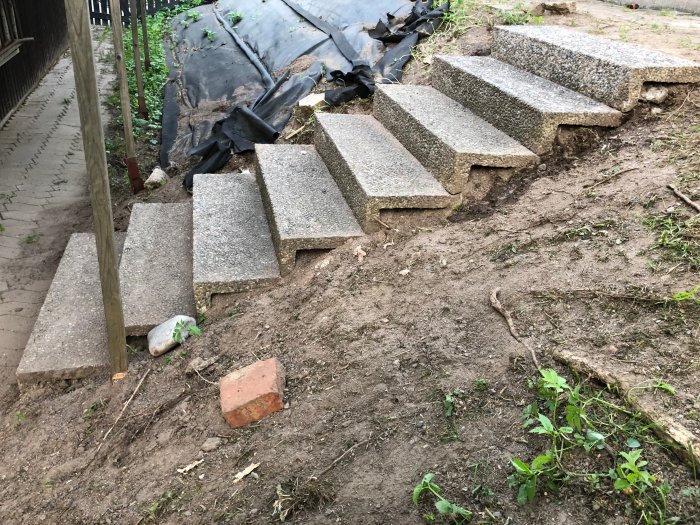 Nygjord trappa bestående av rektangulära betongplattor på en sluttning i en trädgård, ersätter tidigare landslide.