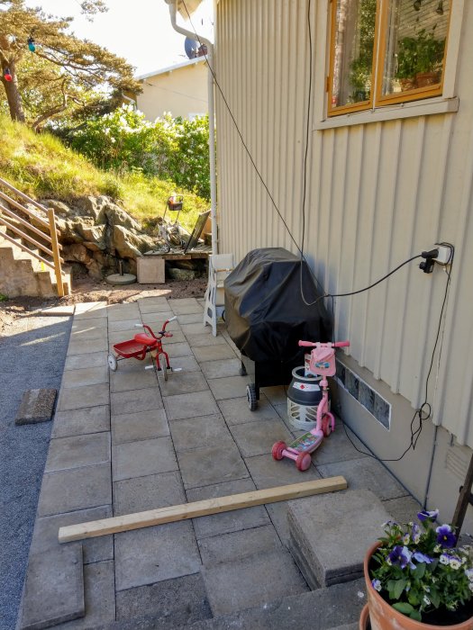 Nyinstallerad skifferslinga bredvid huset, verktyg och barnleksaker synliga, naturscen i bakgrunden.