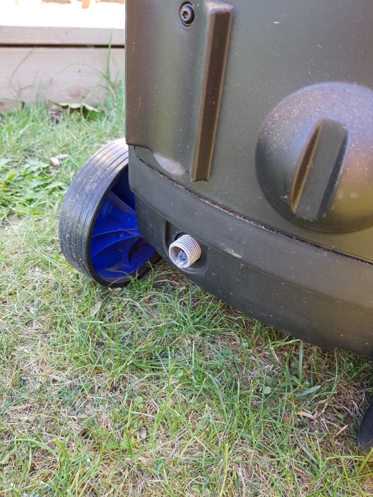 Högtryckstvätt på gräs med vatten som rinner ut genom gängat rör vid hjulet.