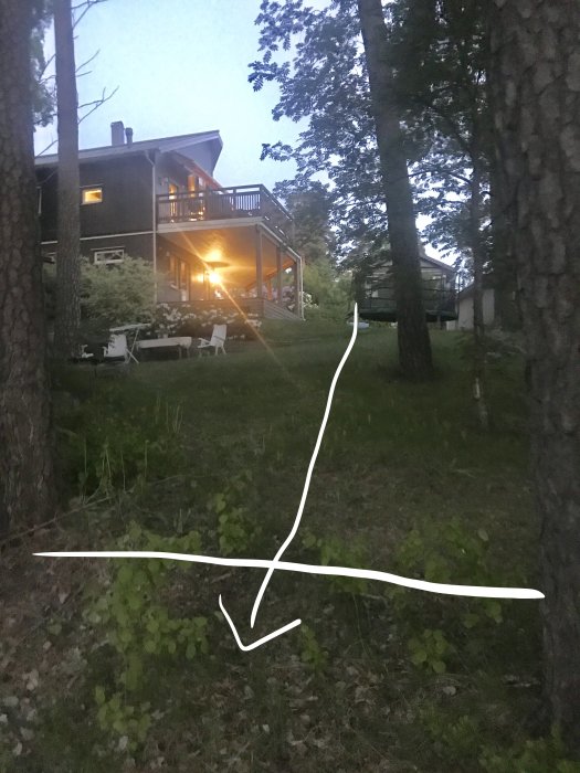 Kvällsbild på en gräsbevuxen tillfartsväg till ett hus, markerad med vit linje, med studsmatta som hinder.