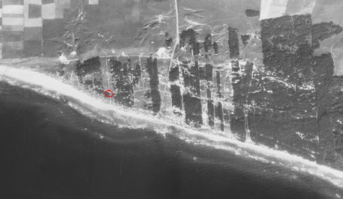 Historiskt flygfoto från 1930-talet med rödmarkerad korsning nära strandlinje.