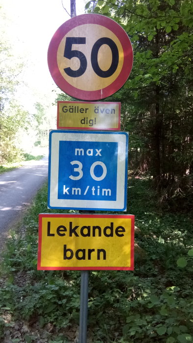 Överhopande trafikskyltar med hastighetsgränser 50 och max 30 km/tim samt varning för lekande barn.