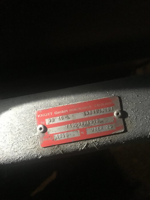Nattbild som visar en röd märkskylt från Knott GmbH med beteckningen VG 10-L monterad på metall.