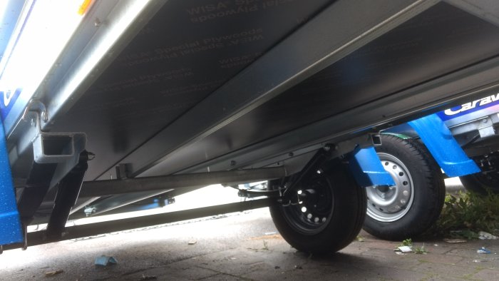 Undersida av en blå och silverfärgad släpvagn med nätgrind, märke Fogelsta LO750U, parkerad utomhus.