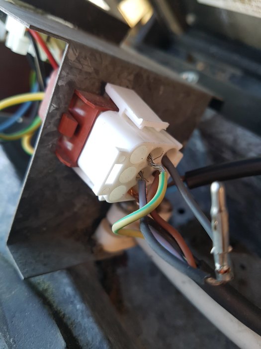 Elanslutning med en vit 9-polig kontakt och färgkodade kablar i ett öppet husventilationsystem.