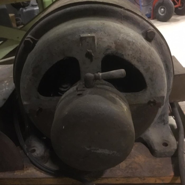 Gammal stor 8-polig elektrisk motor med damm och slitage, synlig vajer och fästmekanism.