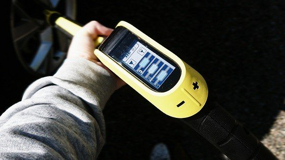 Hand håller en digital däcktrycksmätare med LCD-display och inställningsalternativ.