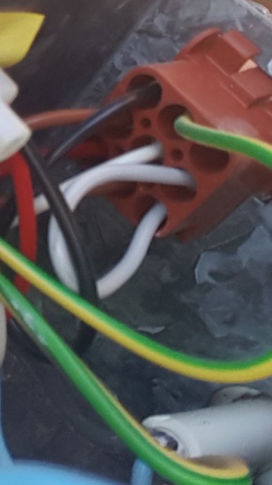 Elkablar anslutna till en röd kopplingsdosa mot en suddig bakgrund.