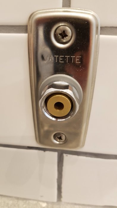 Närbild på en Vatette klämhylsa monterad på ett rör utanför en vägg.