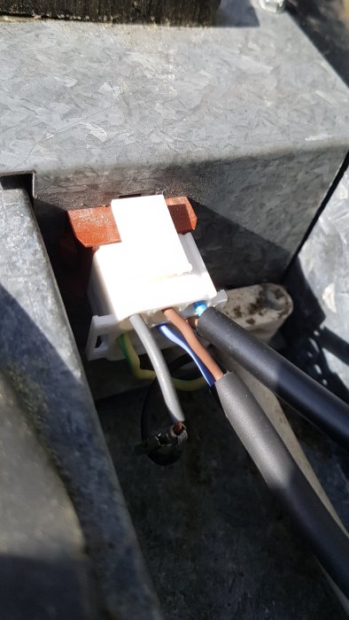 Nyligen omkopplad elektrisk anslutning med nya stift och ordnade kablar i en vit dosa.