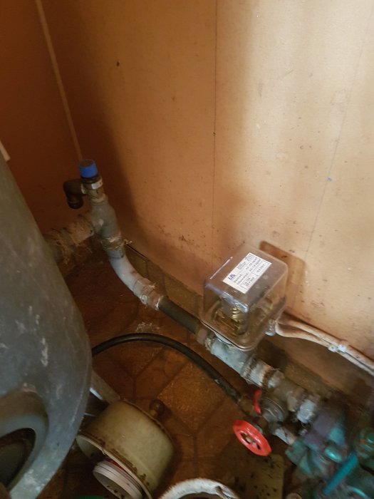 Vattenpump och hydrofor med lågt tryck i ett fritidshus, sida med vred och mätare synlig.