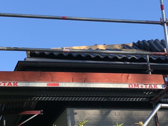 Stort avstånd mellan hängränna och betongtakpannor nära byggnadsställning.