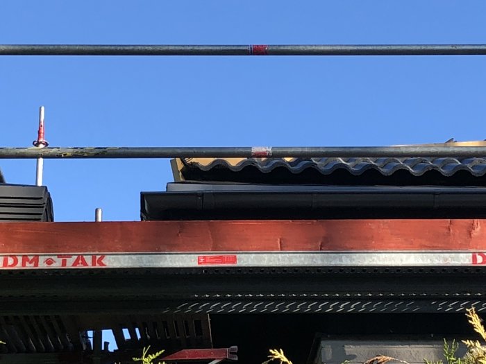 Stort mellanrum mellan svartmålad läkt och hängränna ovanför betongpannor på tak.
