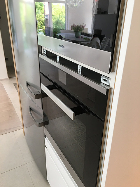 Två inbyggda ugnar med en 35mm mellanrum mellan dem, utrustade med rostfria handtag och placerade i ett ljust kök.