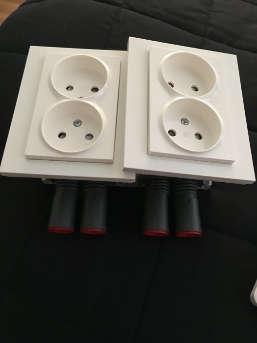 Två vita dubbla eluttag med röda och svarta kablar redo för installation.