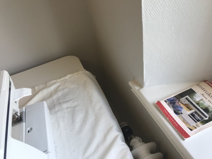 Hörn av rum med radiator framför fönster och tidning på fönsterbrädan, planerat för köksrenovering.