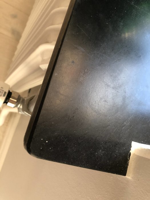 Close-up of a black window sill, potentially made of Eternit, with a white radiator visible underneath.