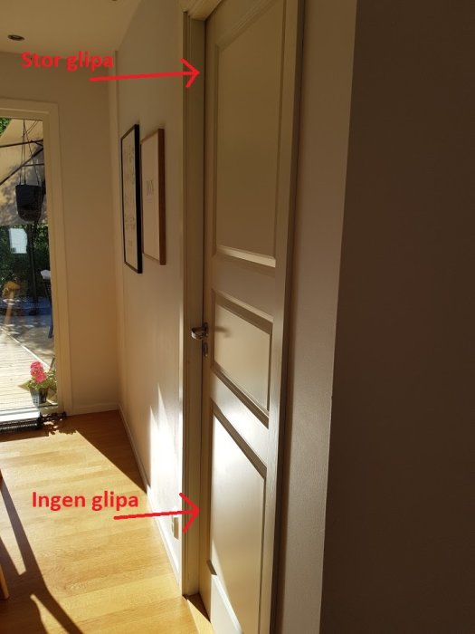 Innerdörr i hemmiljö som lutar och har en stor glipa upptill och ingen glipa nertill.