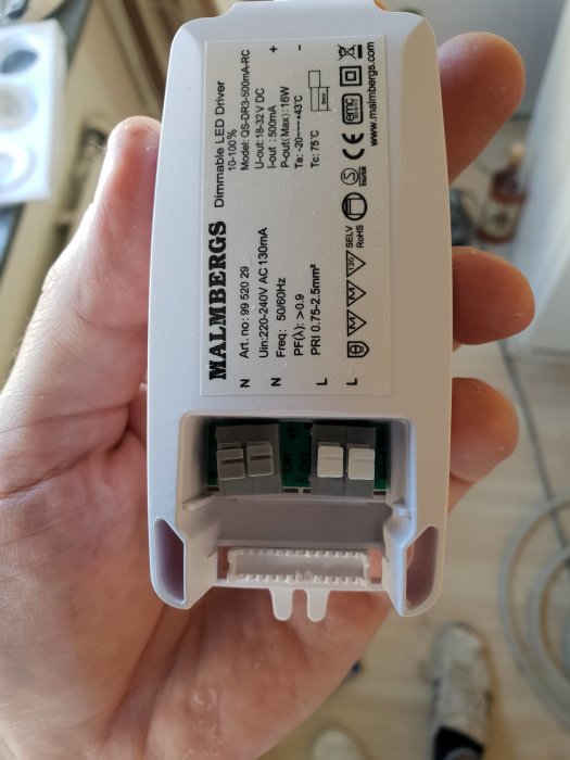 Hand håller en Malmbergs MD-99 dimbar LED-driver för spottar med specifikationer och anslutningar.